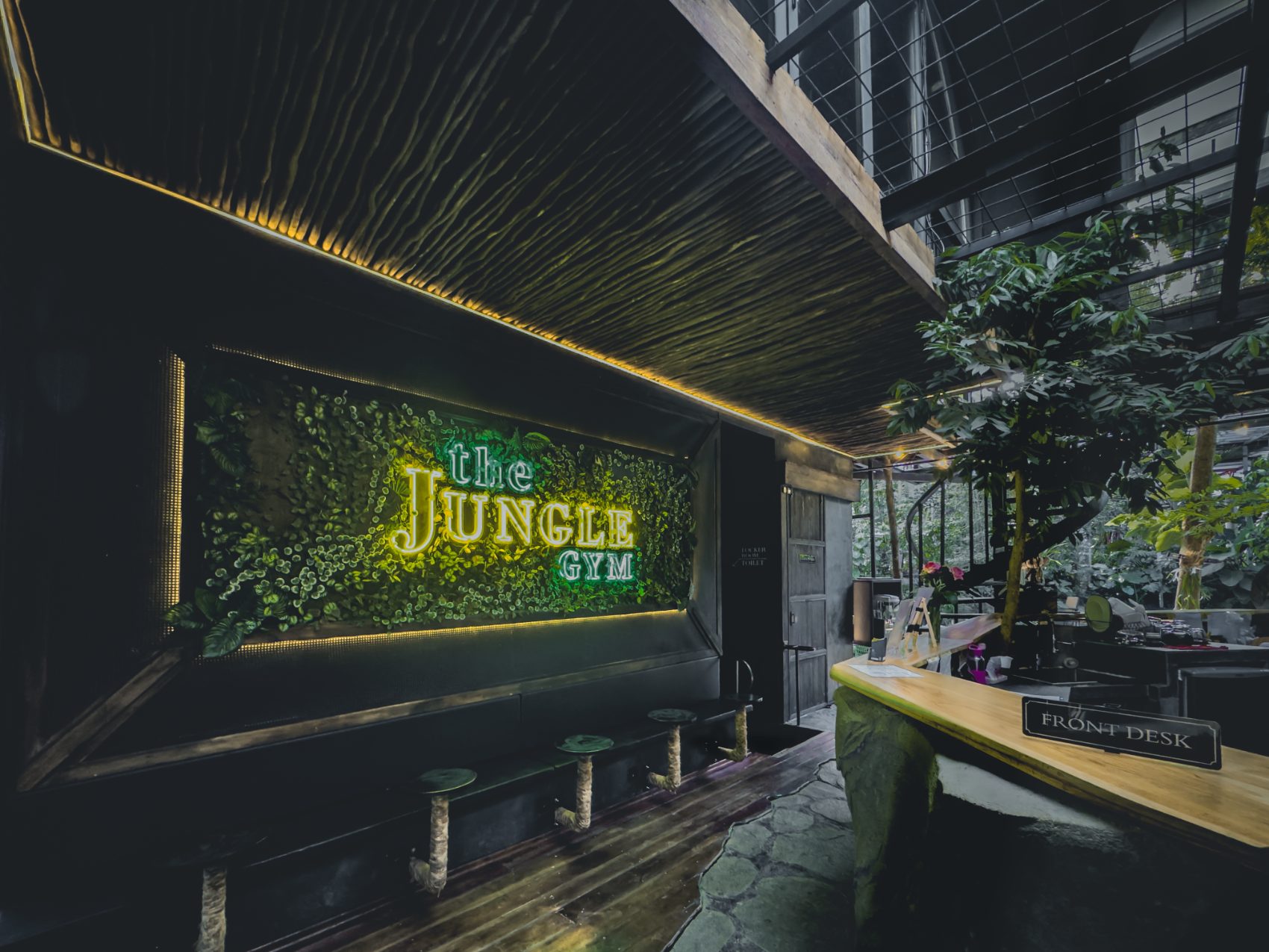Front desk beside a living moss wall carrying the green neon sign